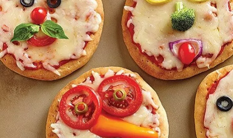 Four mini pizzas decorated with vegetables