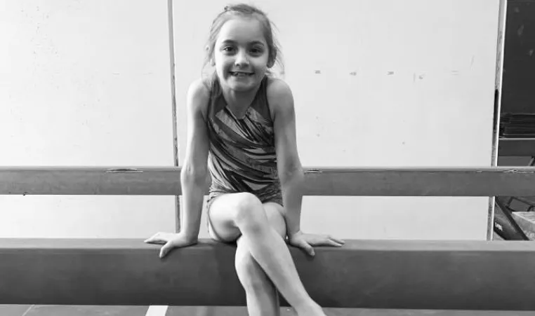 Olivia sitting on a balance beam