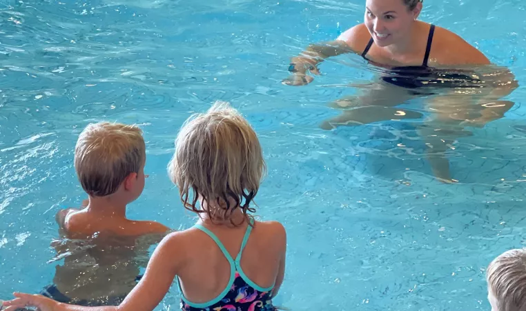 Y SPLASH instructor in the water talking with 2nd graders 