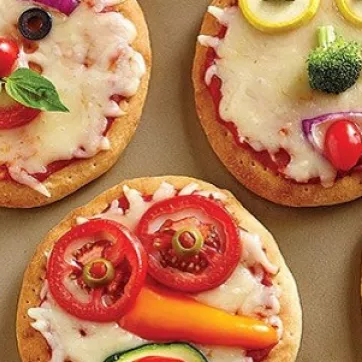 Four mini pizzas decorated with vegetables